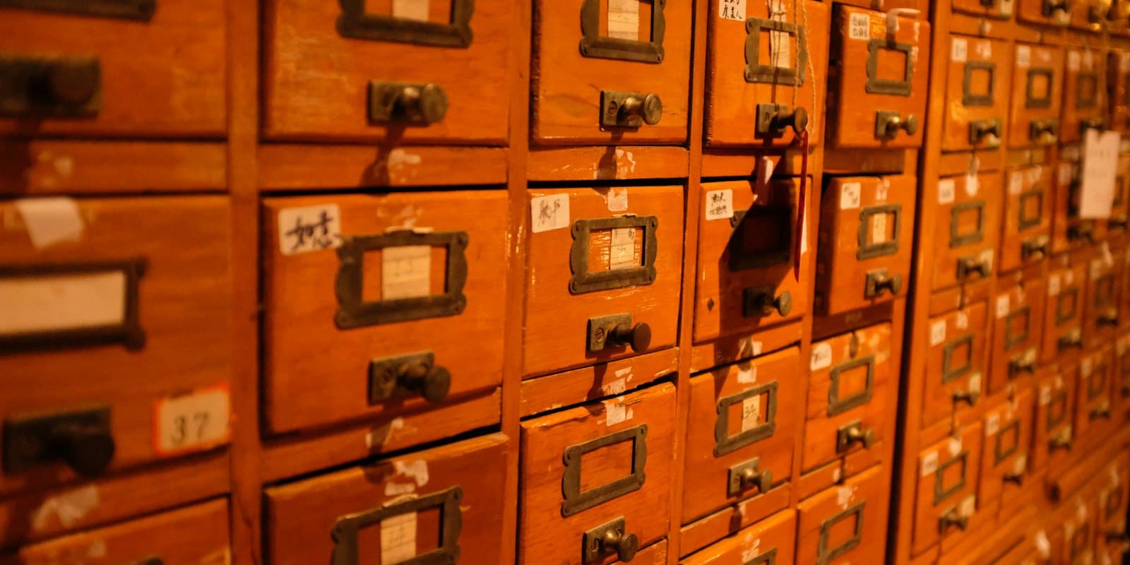 A wall of wooden card-catalog drawers, each with a brass label holder